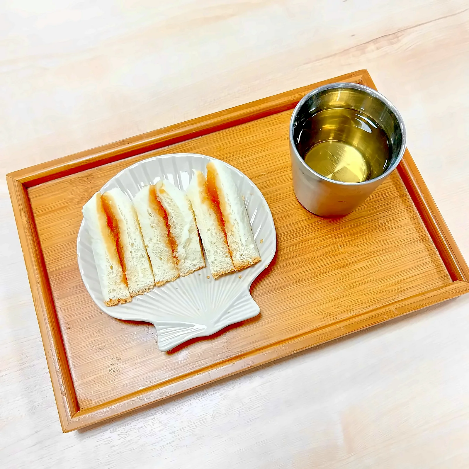 쟁반 위 접시에 담은 샌드위치와 차 한 잔